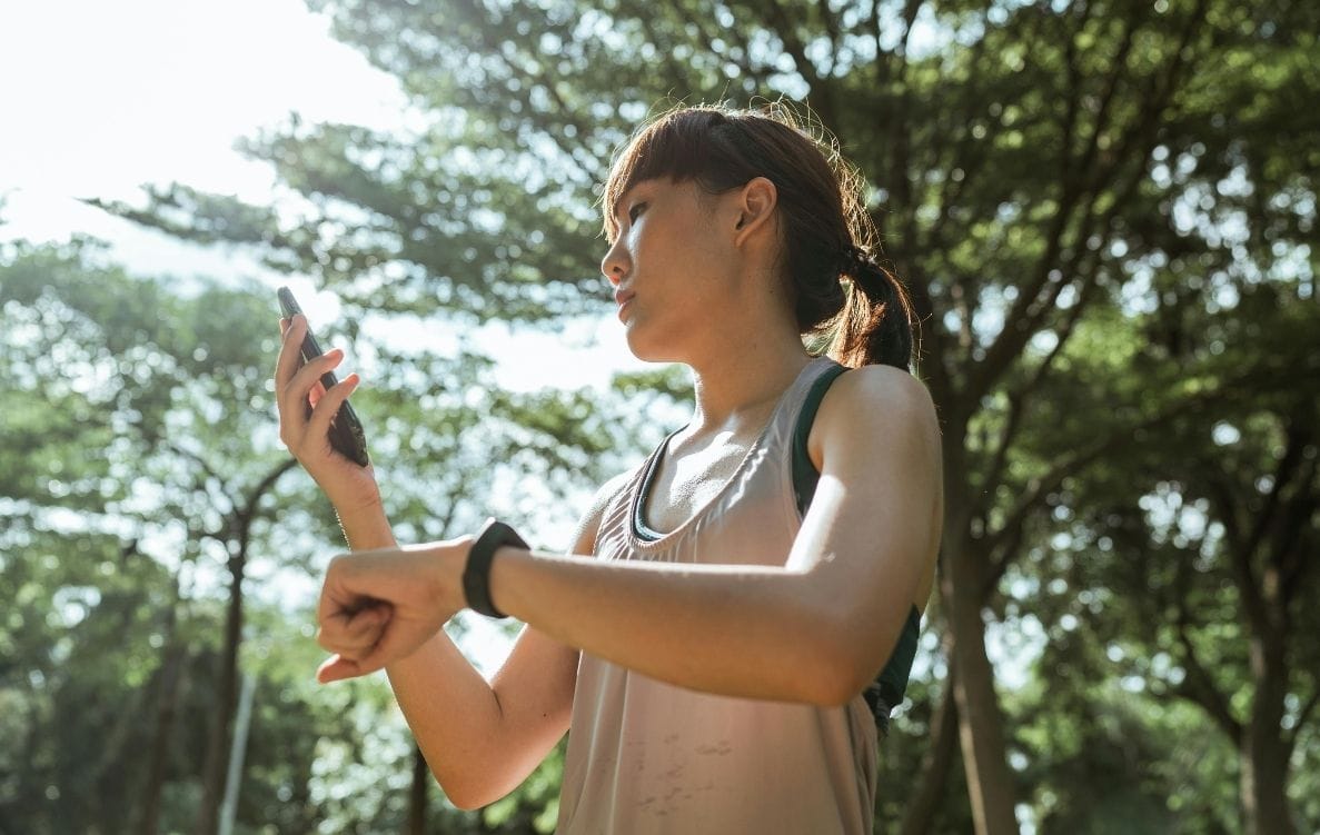 Sporty sportswoman with smartphone and fitness bracelet in park by ketut subiyanto