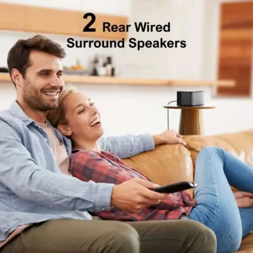A smiling couple cuddles on a leather couch, remote in hand, as they laugh during movie night with two rear wired surround speakers nearby.