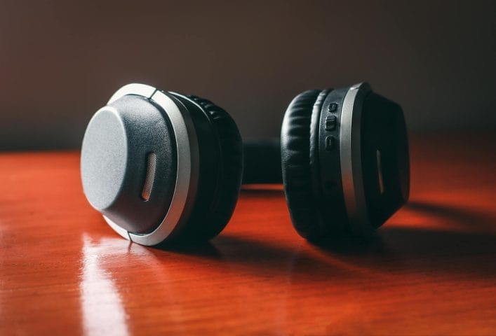 Modern black over-ear headphones shine on polished red wood.