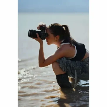 A young woman professional photographer capturing street life with the Nikon Z6 III, showing the camera's portability and sleek design.